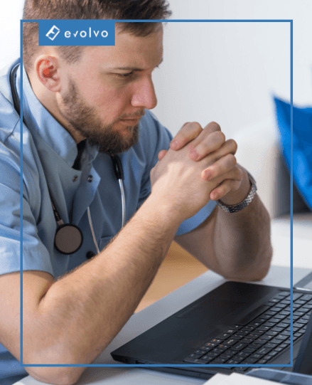Medic îngândurat în fața laptopului